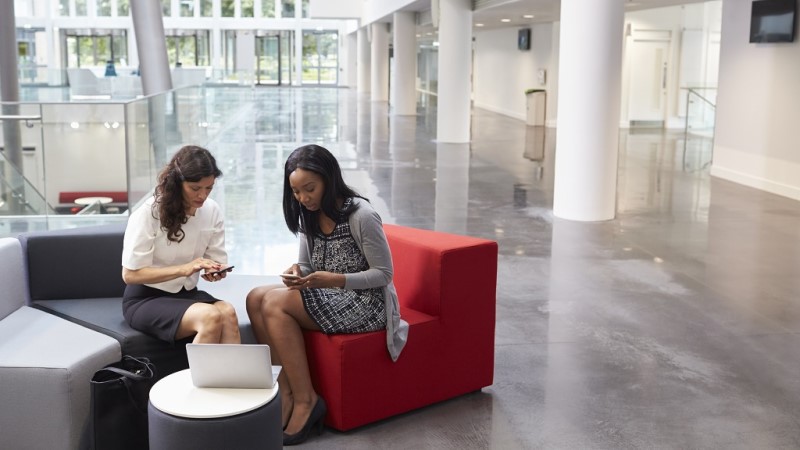 Two female employees are using workplace app in their mobile phones