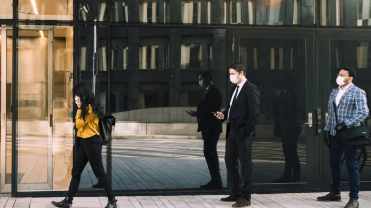 people standing in a queue, maintaining social distancing while wearing a mask at entry