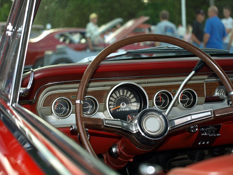 View from classic red convertible through windshield at a car show