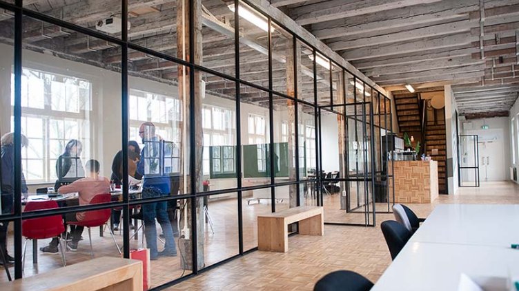 Beautiful modern office space in an old building. A team is working and a woman is making a phone call in the hallway