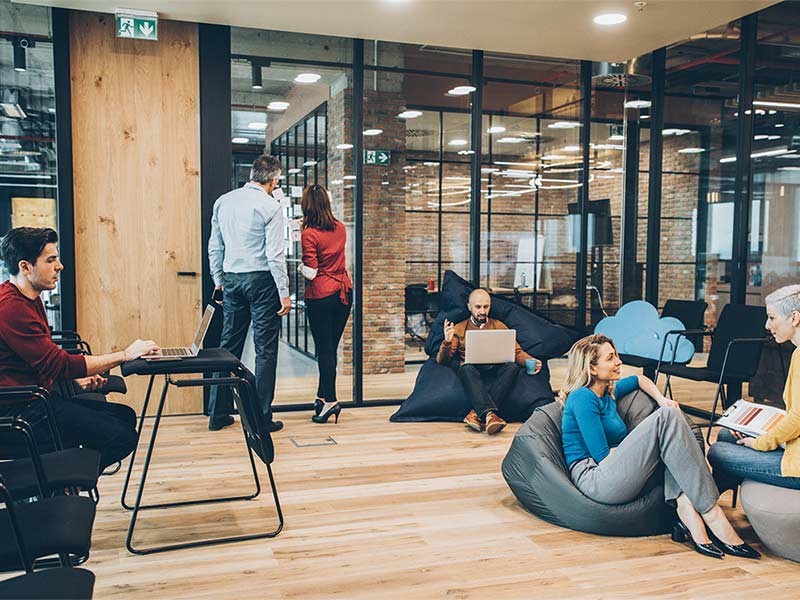 A group of employees work together in a modern workplace lounge area