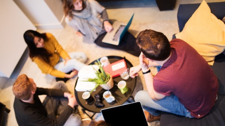 A group of diverse people having coffee and living in a  coliving space