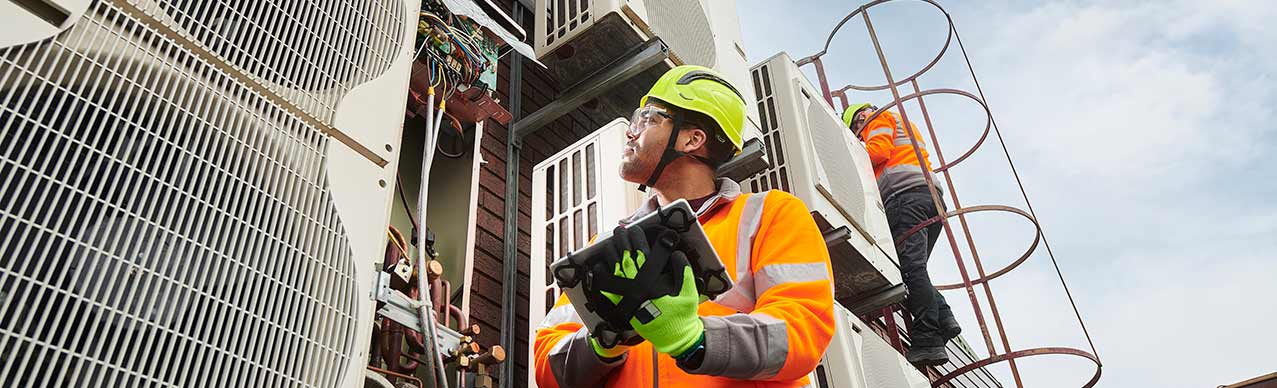 Maintenance engineers inspecting HVAC air conditioning units on a roof