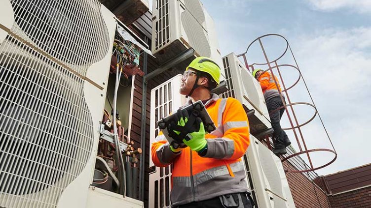 Maintenance engineers inspecting HVAC air conditioning units on a roof